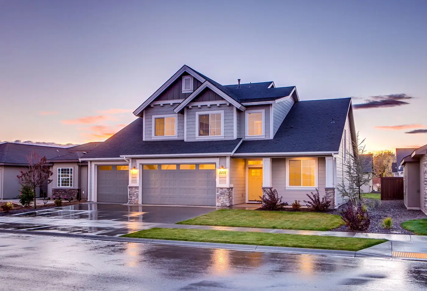 A two-story suburban home at dusk with lights on